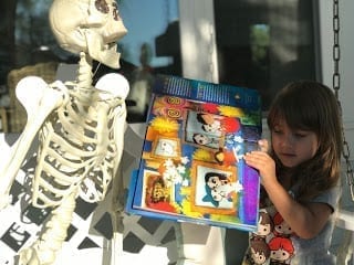Child holding books about Dia de los Muertos or Day of the Dead with Mr. Bones