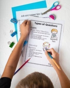 Person drawing on a types of questions anchor chart showing inferential and explicit question types