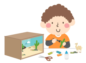 Child with brown hair and orange shirt with a box and cutouts creating a Diorama of a desert scene as part of a fun book project