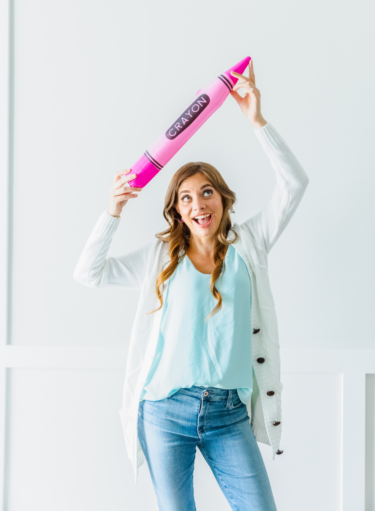 Julie holding a giant pink crayon above her head
